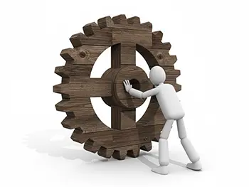 大きな木製の歯車を両手で押して動かそうとしている人物のイラスト