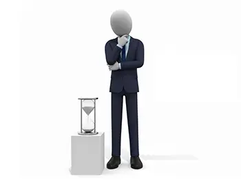 横に置かれた砂時計を見ながら顎に手を当てて考え込むスーツ姿のビジネスマン
