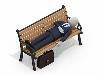 ベンチに横になって眠っているスーツ姿のビジネスマンと、その下に置かれたカバン