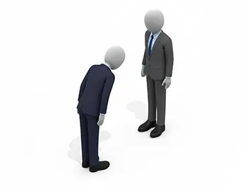 もう一人のビジネスマンの前で深々とお辞儀をするスーツ姿の人物